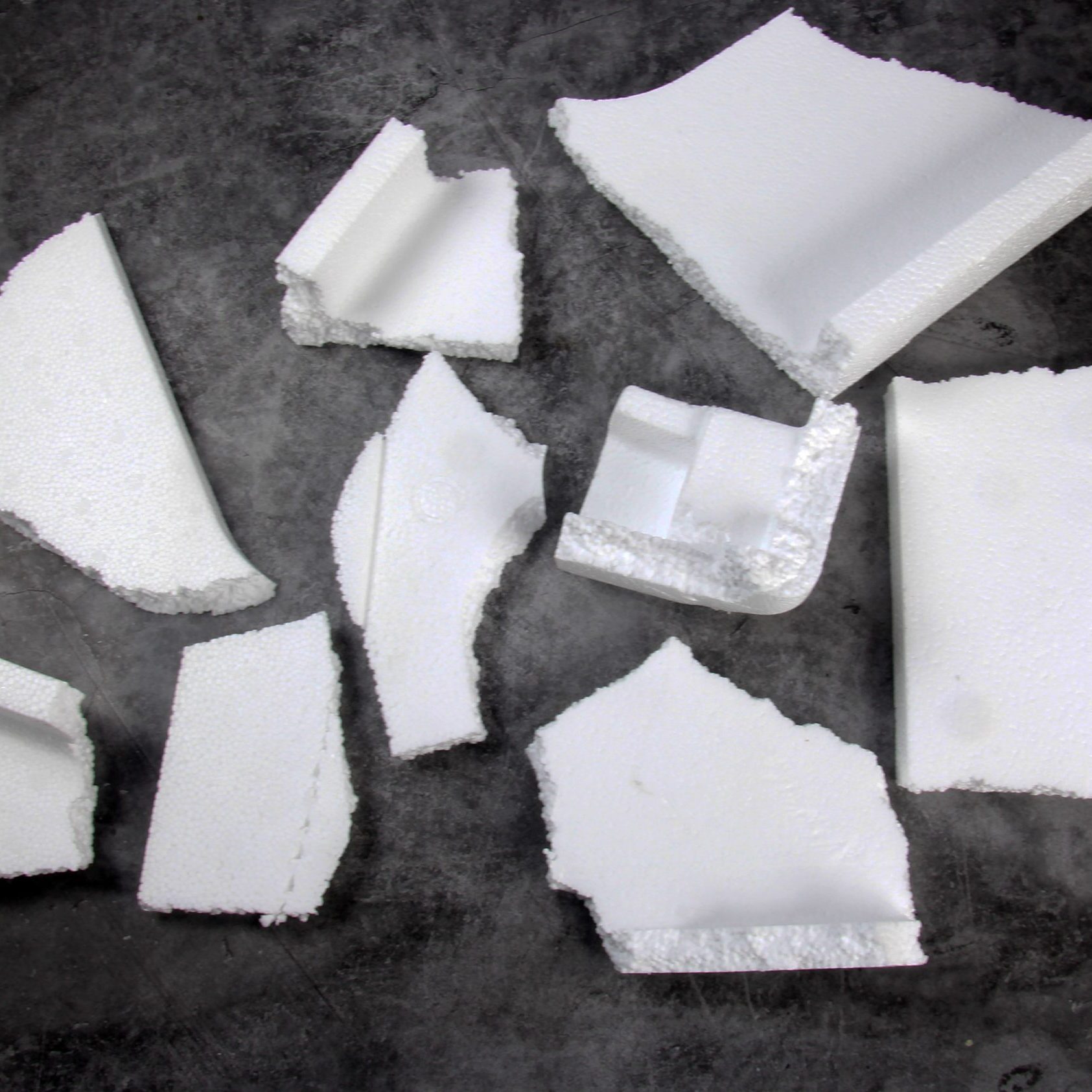 Styrofoam Sheets of different shapes on black background. Pieces of white styrofoam close up. Crumbled styrofoam pieces isolated on dark background Styrofoam Sheets of different shapes on black background. Pieces of white styrofoam close up. Crumbled styrofoam pieces isolated on dark background